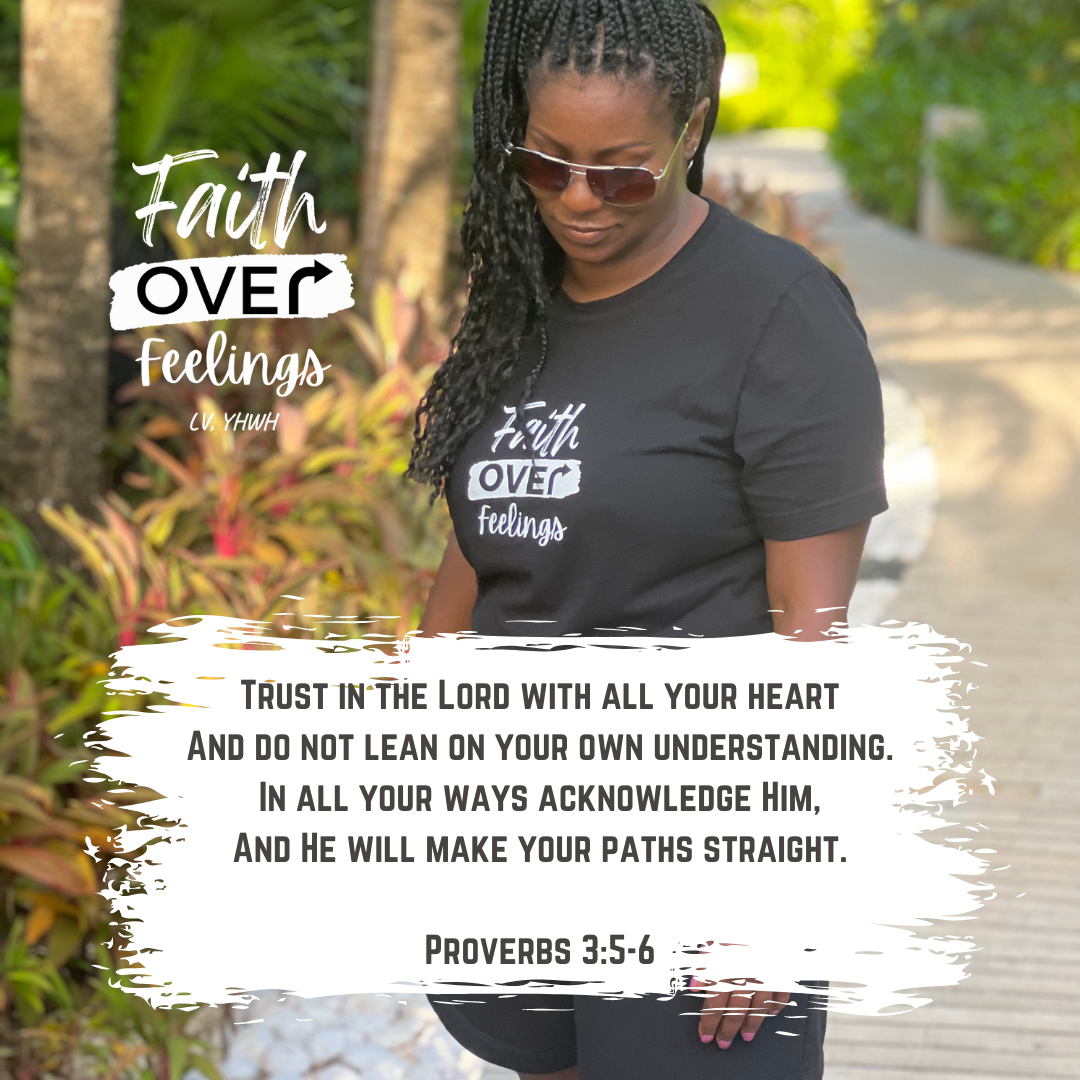 Black woman wearing a black faith over feelings t-shirt outdoors on a garden path with sunglasses